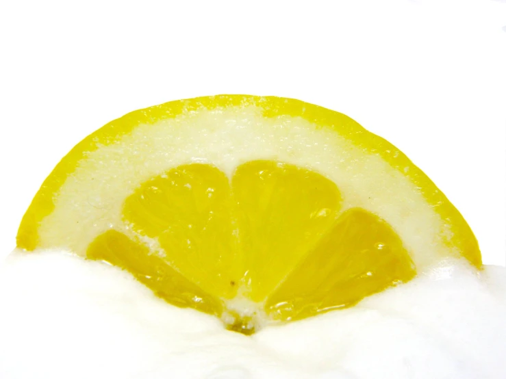 a yellow lemon slice in snow with water droplets on it