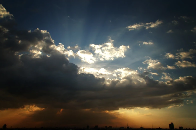 the sun peeking through clouds above a city