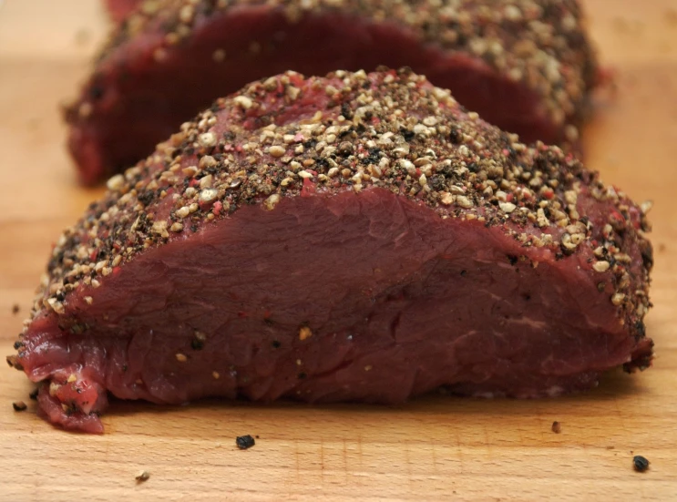 closeup of meat on a wooden board with sprinkles