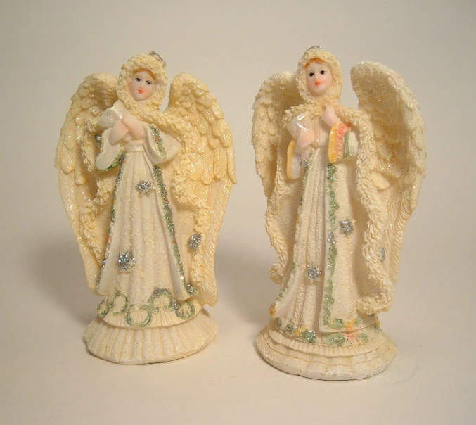 two angel figurines side by side on a white background