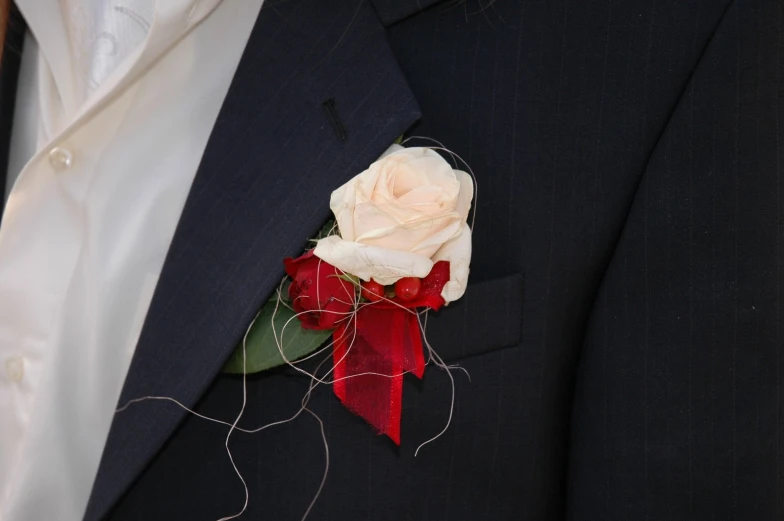 a man wearing a white rose and red bow tie