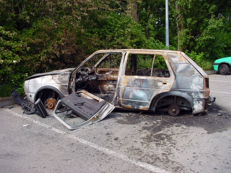 an abandoned, burned car sits in the parking lot