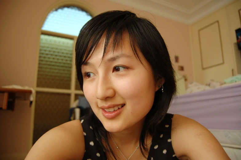 the woman smiles brightly while sitting next to her bed