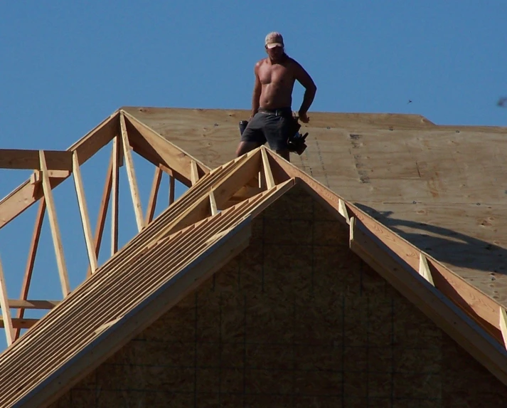 a man standing on top of a roof that is under construction