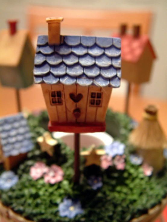 a dollhouse on a small wooden stand surrounded by trees