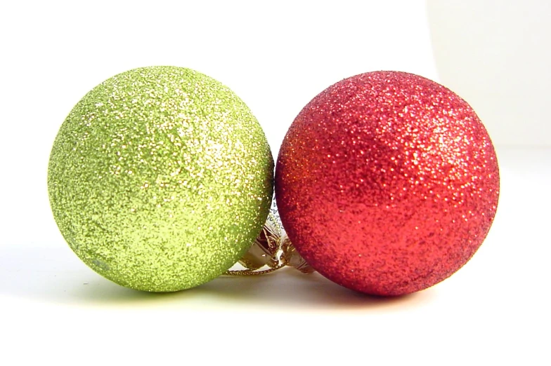 two shiny red and green ornaments on a white background