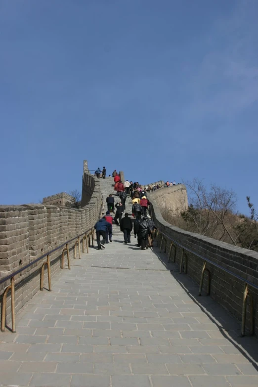 some people are walking along the side of a very long bridge