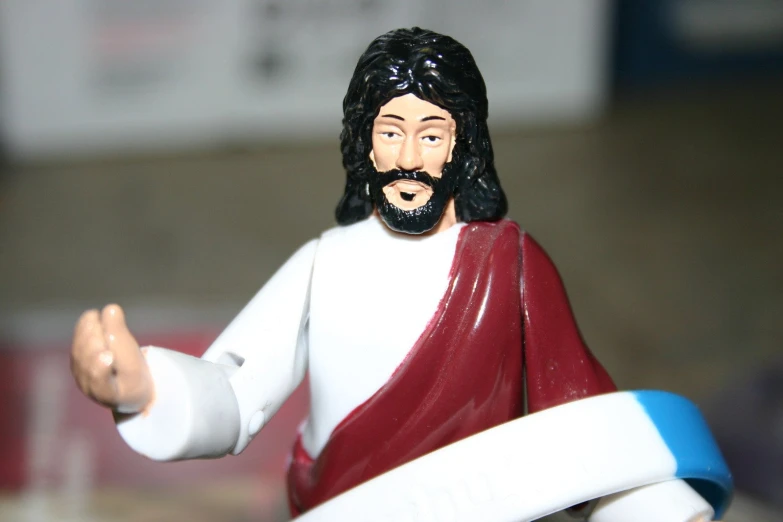 a figurine of jesus is holding a white and blue ribbon