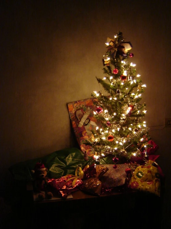 a lit christmas tree with presents in a corner