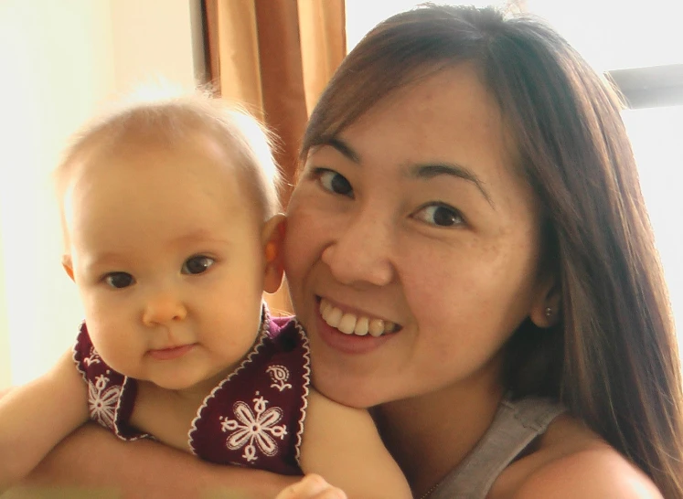 a woman holds a child and smiles for the camera