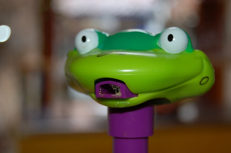 a little frog doll sitting on top of a purple toy