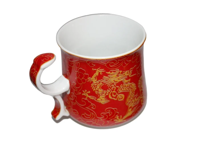 a red coffee cup with an intricate golden design