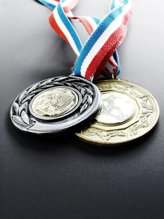 two medals are placed side by side on a black surface