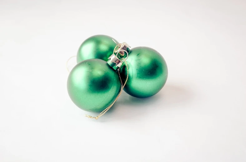 a couple of green christmas ornaments on a white background