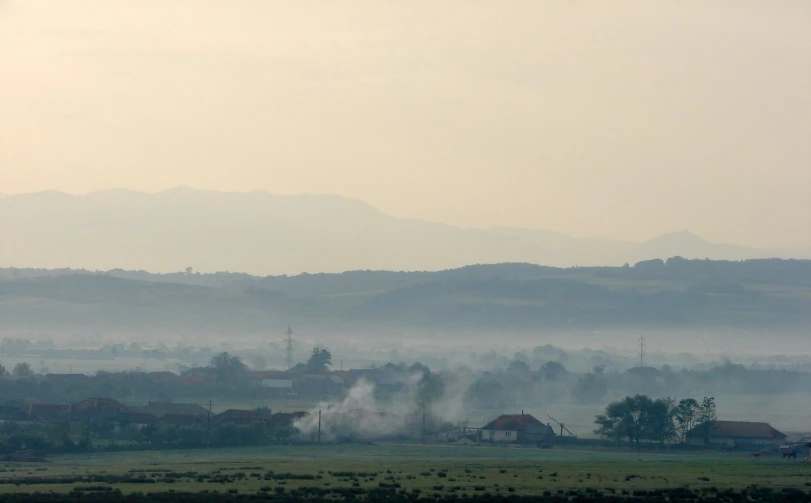 a countryside with green hills in the background and the sky