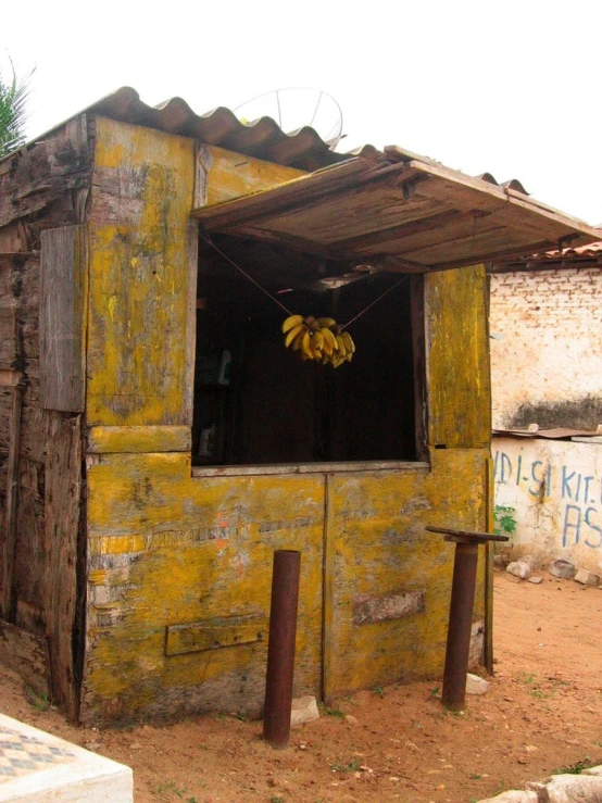 this is an old looking mud hut with some bananas hanging from it