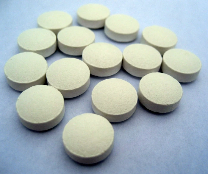 white round pills are scattered on a light blue background