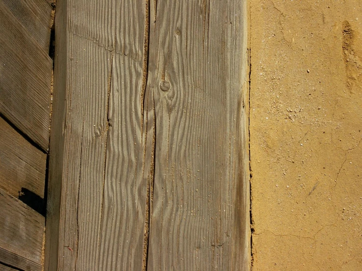 a red bird sits on the side of a wooden fence