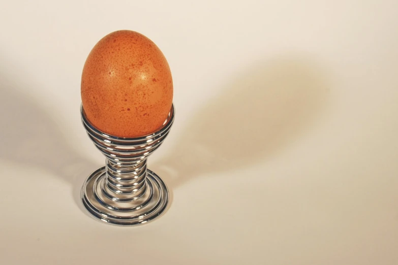 a metal stand holding a chicken egg on it