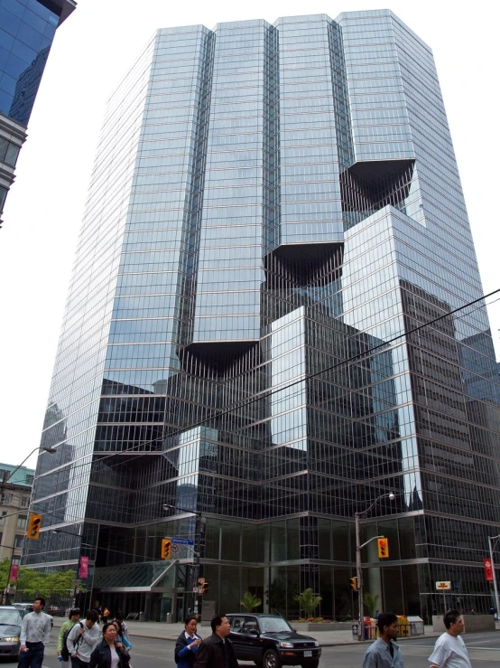 people crossing the street in front of a large modern building