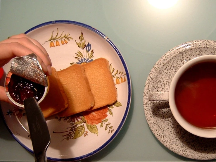 someone is holding a teabag next to a plate with cake and some tea