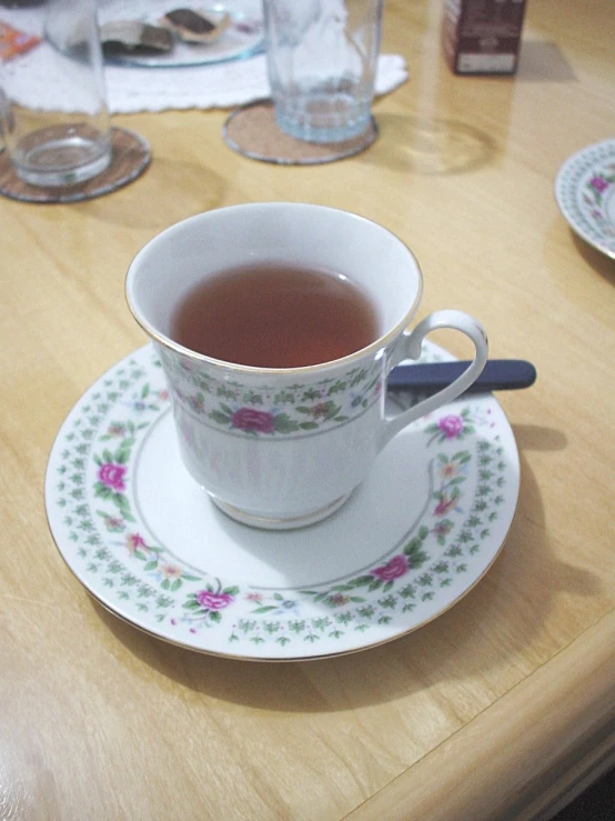 a cup and saucer with a tea in it sits on a wooden table