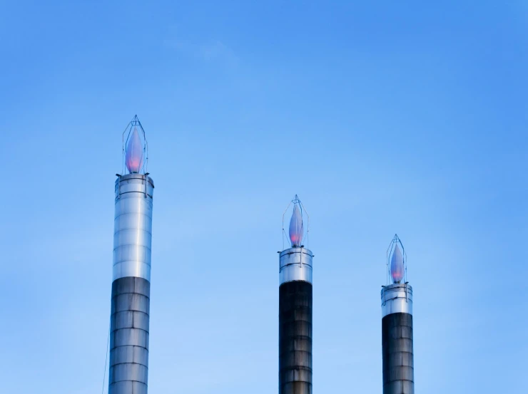 three industrial gas towers in the middle of a blue sky