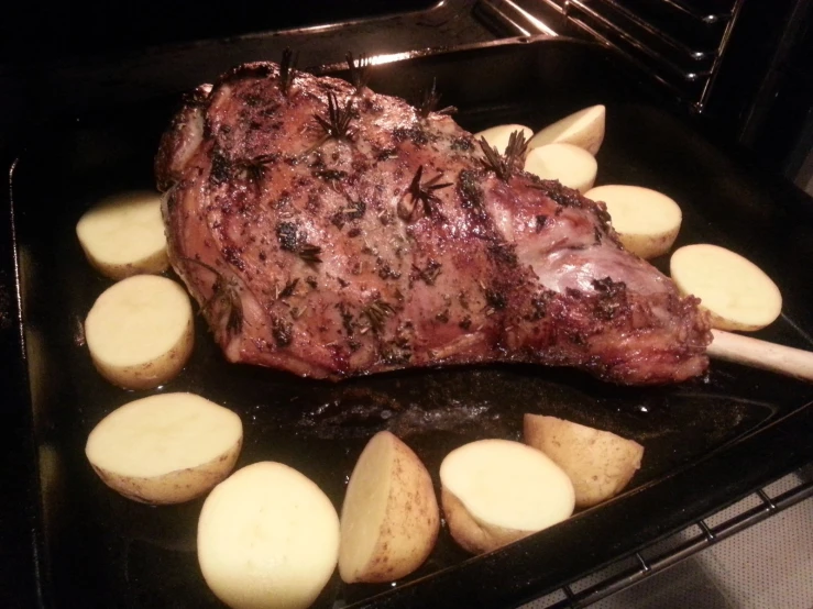 a steak roast on top of some sliced potatoes