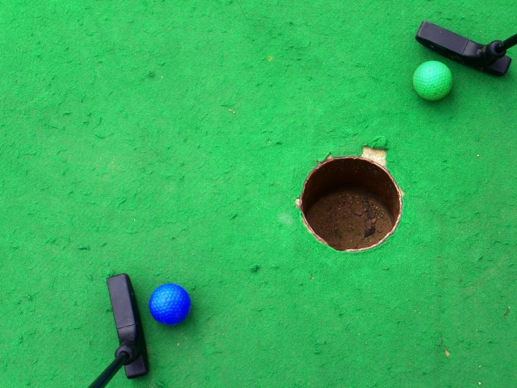 a couple of balls on a putting green next to two different tools