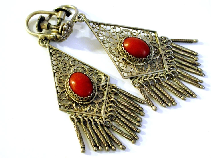 a pair of metal earrings with orange stones