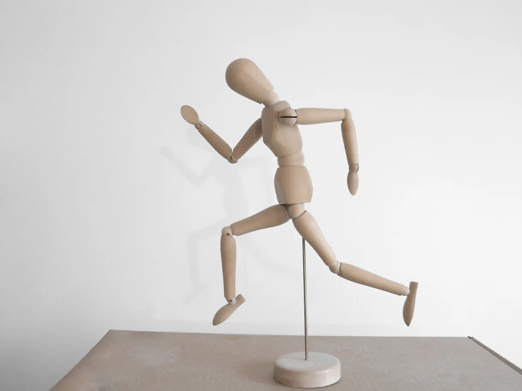 a wooden dummy in front of a white wall