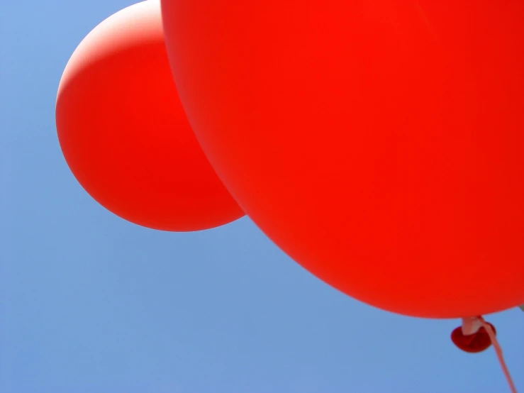 three red balloons floating together in the air