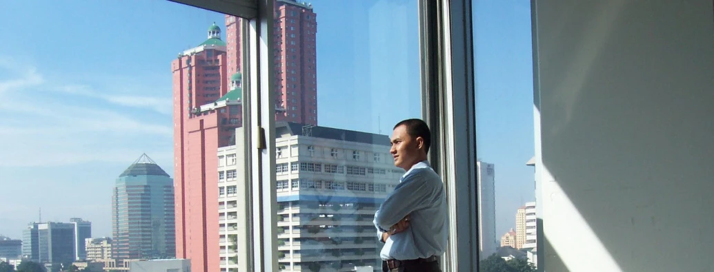 a man is standing by a large window