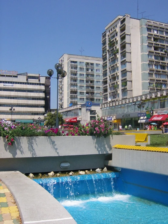 water fountain is surrounded by small beds with flowers on top of it