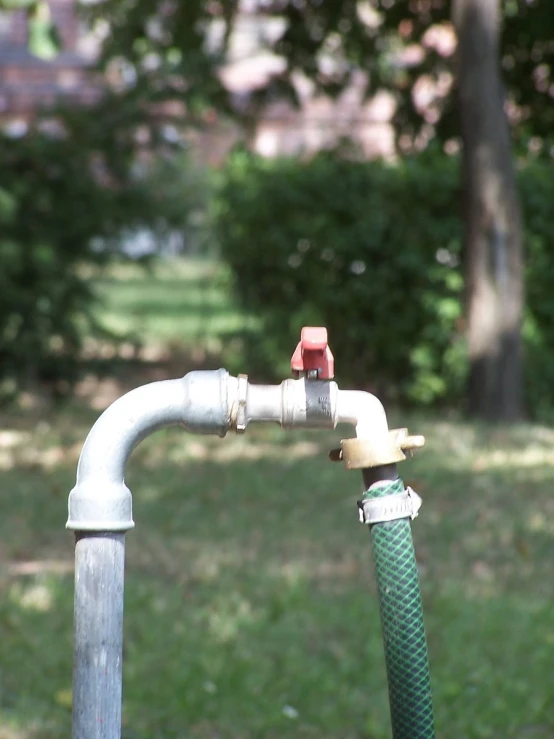 a water hose connected to a metal pipe in the grass