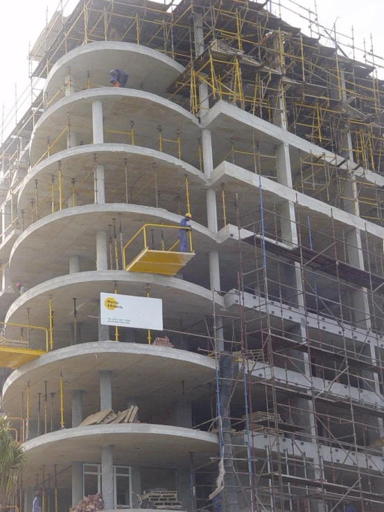 a crane is standing by a tall building under construction