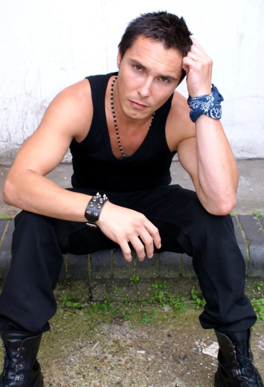 a young man with a watch and celet sitting on a bench