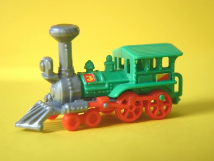 a toy train is sitting on a yellow surface