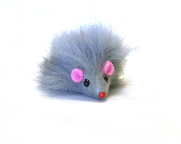 a small stuffed animal with pink ears on white surface