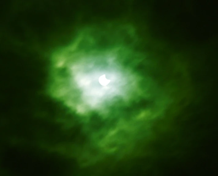 the bright green sun appears to be partially obscured by dark clouds