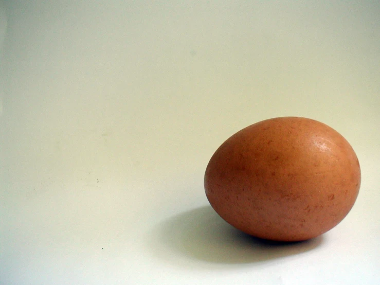 a brown egg sitting on top of a white surface
