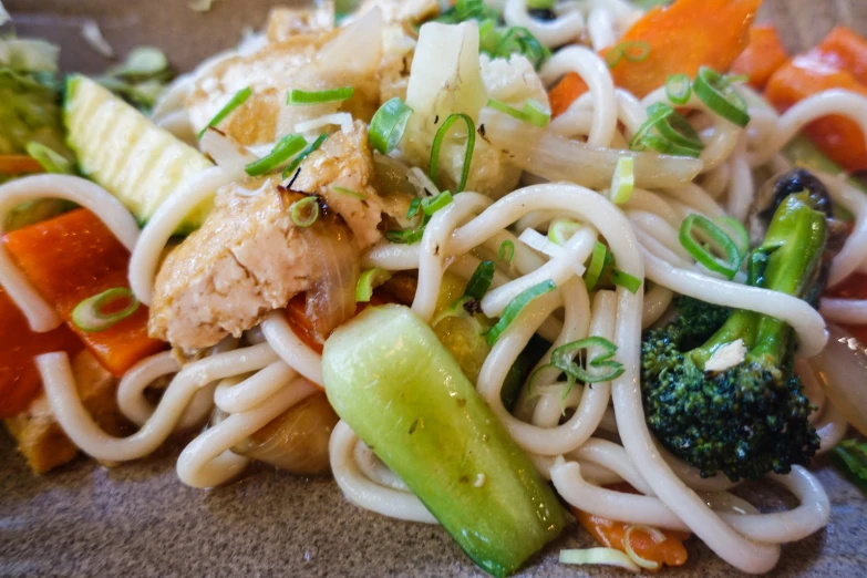 a meal that is on a plate and has noodles, vegetables, chicken and cheese on it