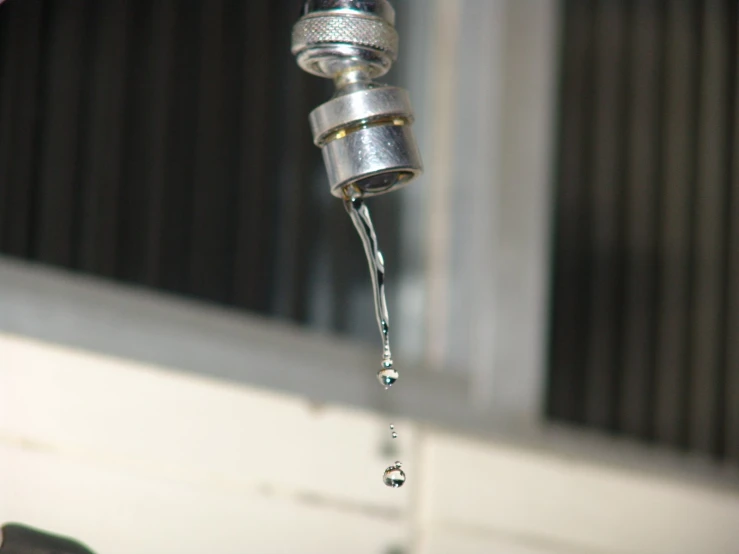 the silver faucet has some water flowing from it