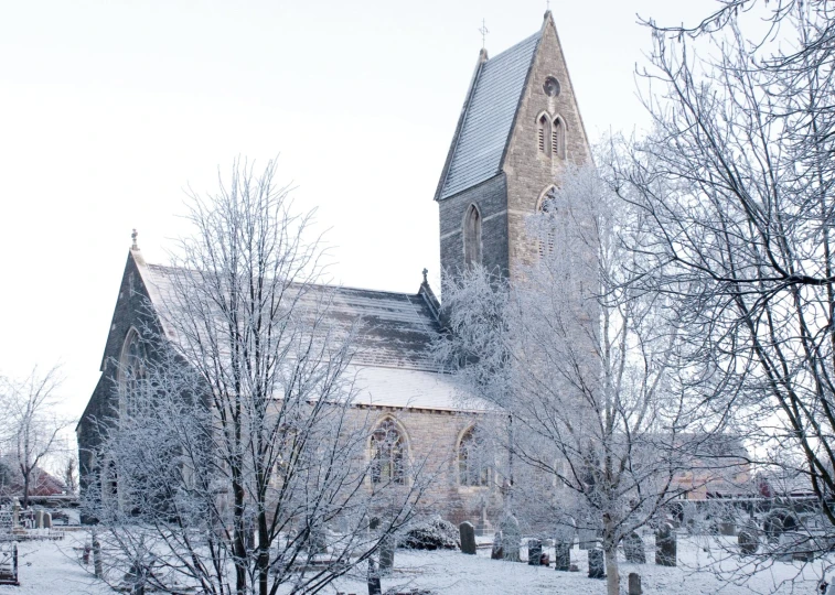 a church with a big window, some trees, and snow