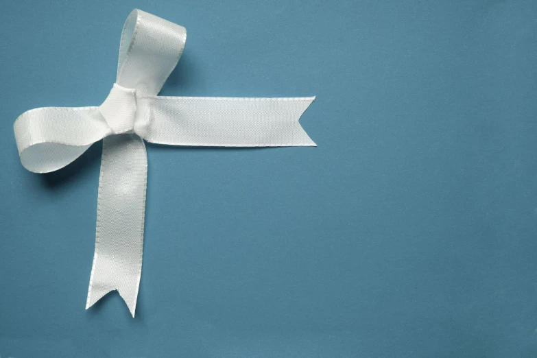 white ribbon with a bow on it sitting against a blue wall