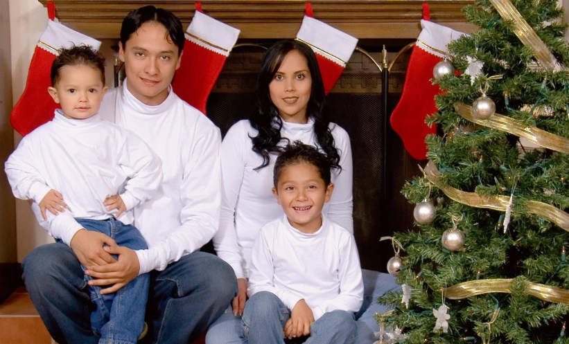 a family sits together next to a christmas tree