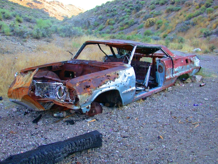 a run down car that has rusted out with its hood open