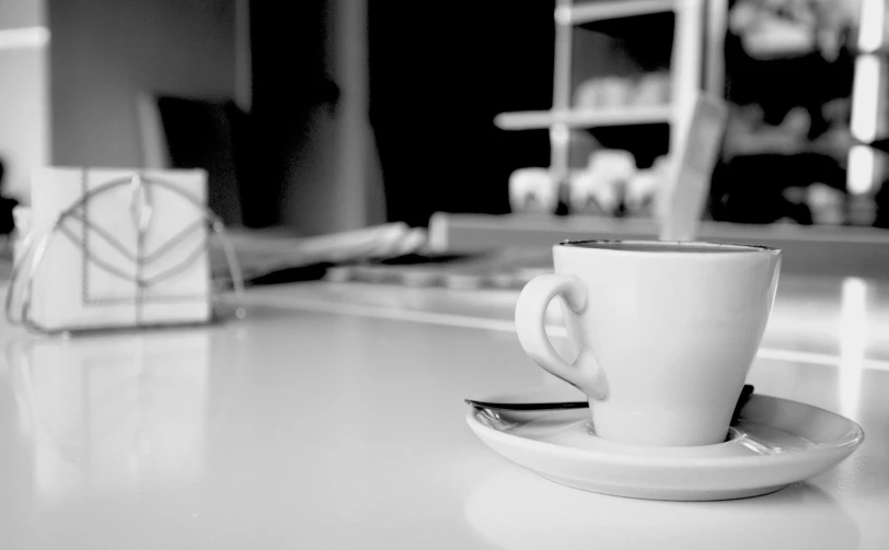 a cup and spoon sits on a table in a black and white po