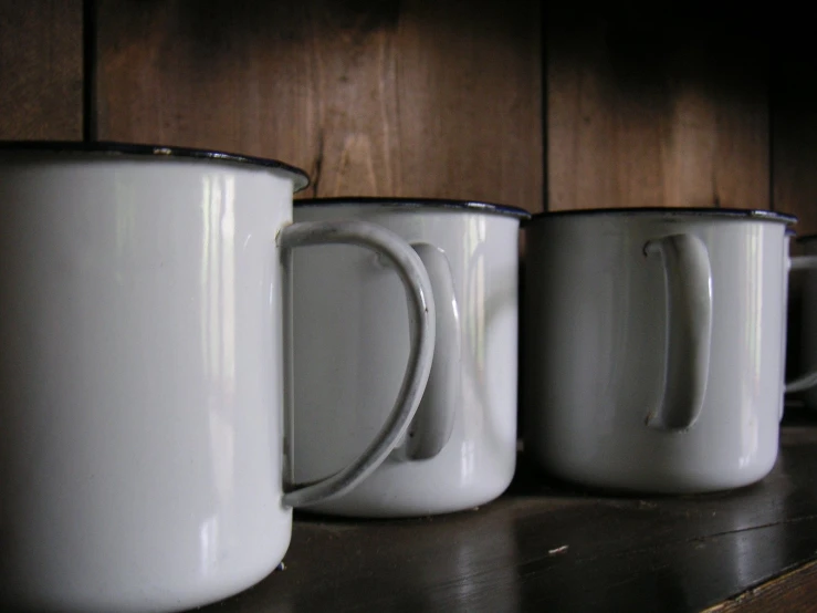 three white coffee mugs sitting next to each other on a shelf
