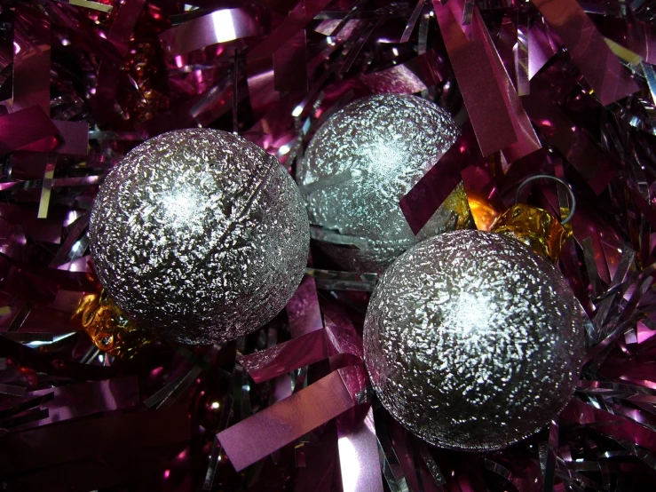 two silver ornaments sitting on top of purple ribbons